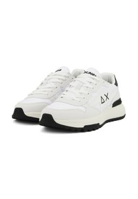 Scarpe da ginnastica bianche con suola nera, dotate di una tomaia testurizzata, punta rotonda e stringhe. Accenti del logo sul lato e sulla linguetta.