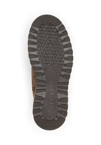 Bruine leren schoen met een gestructureerde rubberen zool. De zool heeft een hexagonaal patroon en opvallende noppen voor grip. Merkennaam gedrukt.