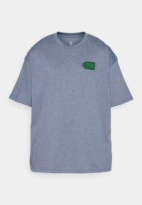 Grå kortærmet t-shirt lavet af blødt stof, med et grønt basketballgrafik med "96" på venstre brystområde. Afslappet pasform.