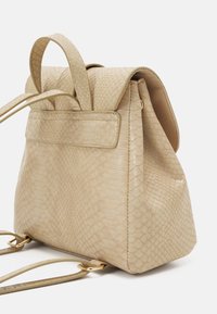 Mochila beige con un patrón texturizado de piel de serpiente. Cuenta con dos asas superiores, cierre con solapa y detalles en hardware de tono dorado.