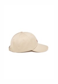 Beige cap with a curved visor, made of smooth fabric. Features stitching details and ventilation holes along the side.