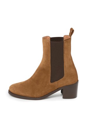 Bottine en suède marron avec panneau élastique sur le côté, languette à l'arrière et petit talon bloc, sur fond blanc.