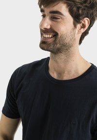 Granatowy bawełniany t-shirt z okrągłym dekoltem i krótkimi rękawami, z małym logo na klatce piersiowej. Gładka tekstura i luźny fason.