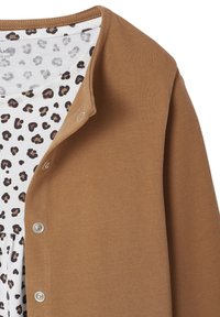 Brauner Cardigan mit strukturierter Oberfläche, ausgestattet mit metallenen Druckknöpfen. Darunter ein weißes Kleidungsstück mit einem schwarz-braunen Leopardenmuster.