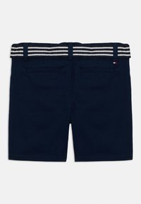 Shorts bleu marine avec deux poches passepoilées à l'arrière et une ceinture rayée noire et blanche passant à travers des passants de ceinture bleu marine.
