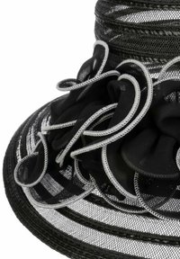 Schwarzer Hut mit breitem Rand aus strukturiertem Netzdesign und gestuften Stoffblumen. Verfügt über silberne Akzente entlang der Ränder der Blumen und des Randes.