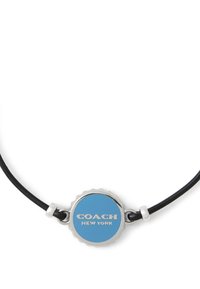 Bracelet en cordon cuir noir avec un pendentif circulaire bleu bordé d'argent, affichant "COACH NEW YORK" en lettres blanches.