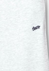Lichtgrijze sweatshirtstof met een zachte textuur en een klein donker geborduurd logo aan de linkerkant.