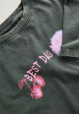 Mörkgrön bomullströja med ett grafiskt tryck av rosa körsbär och texten "BEST DAY EVER" i rosa stiliserad lettering.