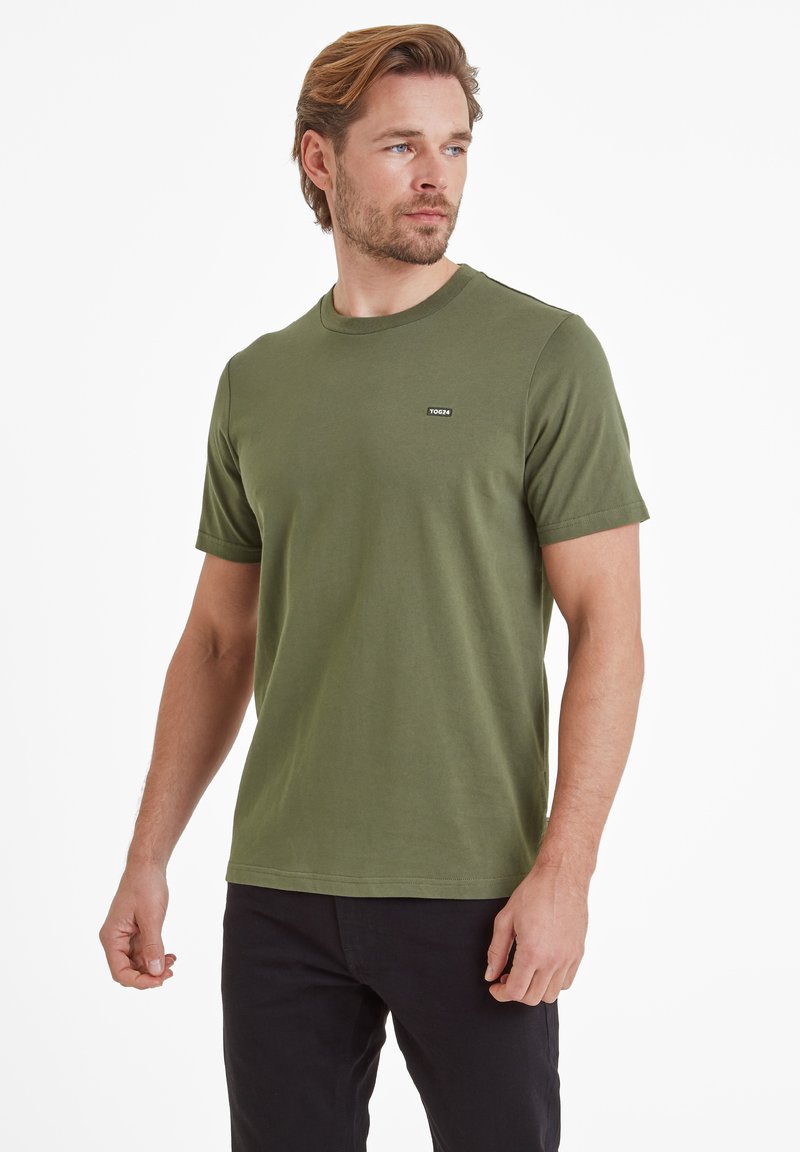 Olive green crewneck t-shirt made of soft cotton. Features short sleeves and a small black logo on the left chest. Simple design.