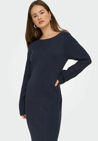 Abito a maglia a costine blu navy con scollatura a barca, maniche lunghe e silhouette aderente. Presenta un motivo testurizzato e un design di lunghezza media.