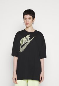 Must värvi suurem polo, mis on valmistatud puuvillast, esiküljel on aukudega kollane Nike logo. Lühikesed varrukad ja ümmargune kaelus.
