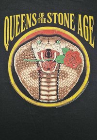 Cobra enroscada con ojos verdes sosteniendo una rosa roja en la boca, rodeada de un anillo amarillo y rojo, con el texto "Queens of the Stone Age" arriba.