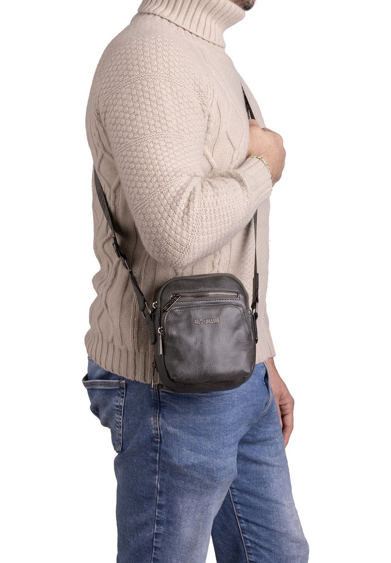 Borsa a tracolla in pelle nera texturizzata, con tasca con zip e tracolla regolabile. Design compatto e quadrato, caratterizzato da un logo sottile.