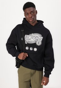 Sweatshirt com capuz preto e estampagem gráfica com detalhes em branco e cinza. O tecido é macio, com punhos canelados e um bolso frontal.