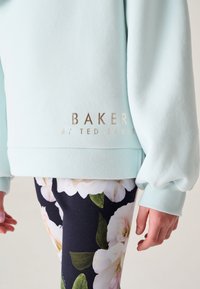 Lichtblauwe sweatshirt met geribde manchetten, voorzien van gouden tekst "BAKER by TED BAKER" op de zoom, gecombineerd met bloemenprint legging.