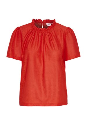 Punainen lyhythihainen pusero, jossa on röyhelökaulus ja teksturoitu kangas, jossa on geometrinen kuvio. Tavallinen istuvuus ja hieman puffattuja hihoja.