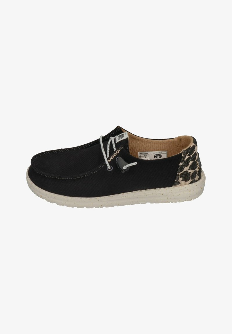 Black canvas slip-on shoe with white laces, a speckled rubber sole, and a leopard print accent at the heel.