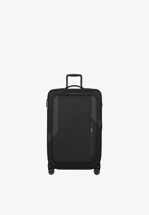 Black upright soft-shell suitcase with four spinner wheels, extended telescopic handle, front zip pocket, and top carry handle.