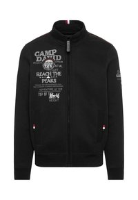 Black zip-up jacket with a high collar. Features printed text and a badge on the front, contrasting stitching, and ribbed cuffs.