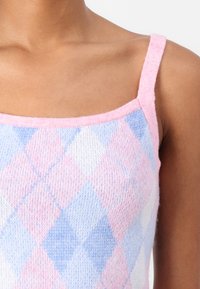 Knit tank top featuring a pastel pink and blue argyle pattern, with thin straps and a squared neckline. Soft, textured fabric.