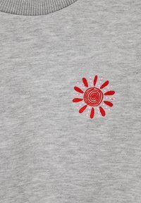 Šedá látka s červeno-ružovým vyšitým spirálovým slnečným vzorom pri žebrovanom golieri.