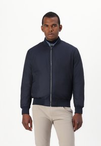 Marine bomberjakke med glidelås foran, ribbestrikkede mansjetter og nederkant, lett materiale, med rund krage og sidelommer.