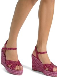 Sandali con zeppa rosa, con una piattaforma tessuta e strutturata e un cinturino decorato con strass. Design a punta aperta con cinturino alla caviglia regolabile.
