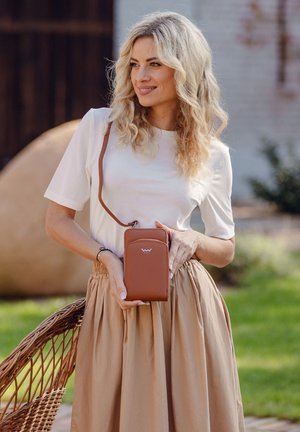 Braune Kunstleder-Crossbody-Tasche mit schlankem Design, ausgestattet mit einer Fronttasche und einem langen, verstellbaren Tragenriemen. Abgebildet mit einem hellen Oberteil und einem beigen Rock.