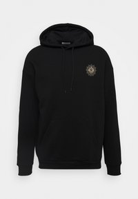Black hoodie made from soft fabric, featuring a front pouch pocket and an embroidered gold lion emblem on the left chest.