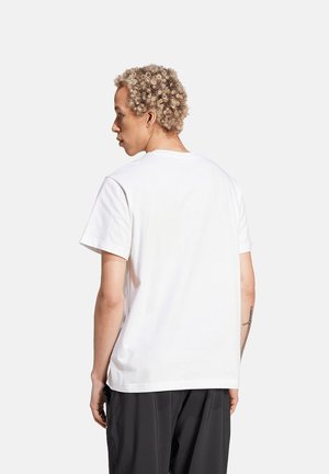 Weißes Baumwoll-T-Shirt mit lockerer Passform, rundem Ausschnitt und kurzen Ärmeln. Keine sichtbaren Muster oder Grafiken. Einfache und glatte Textur.