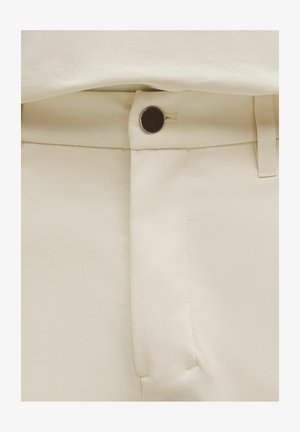 Kalhoty krémové barvy s hladkou texturou, vybavené viditelným zapínacím knoflíkem a čistým designem pasu.