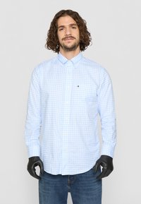 Lyseblå gingham ternet skjorte med knap-ned krave, lange ærmer og et lille logo. Tæt design i bomuldsstof; glat tekstur.