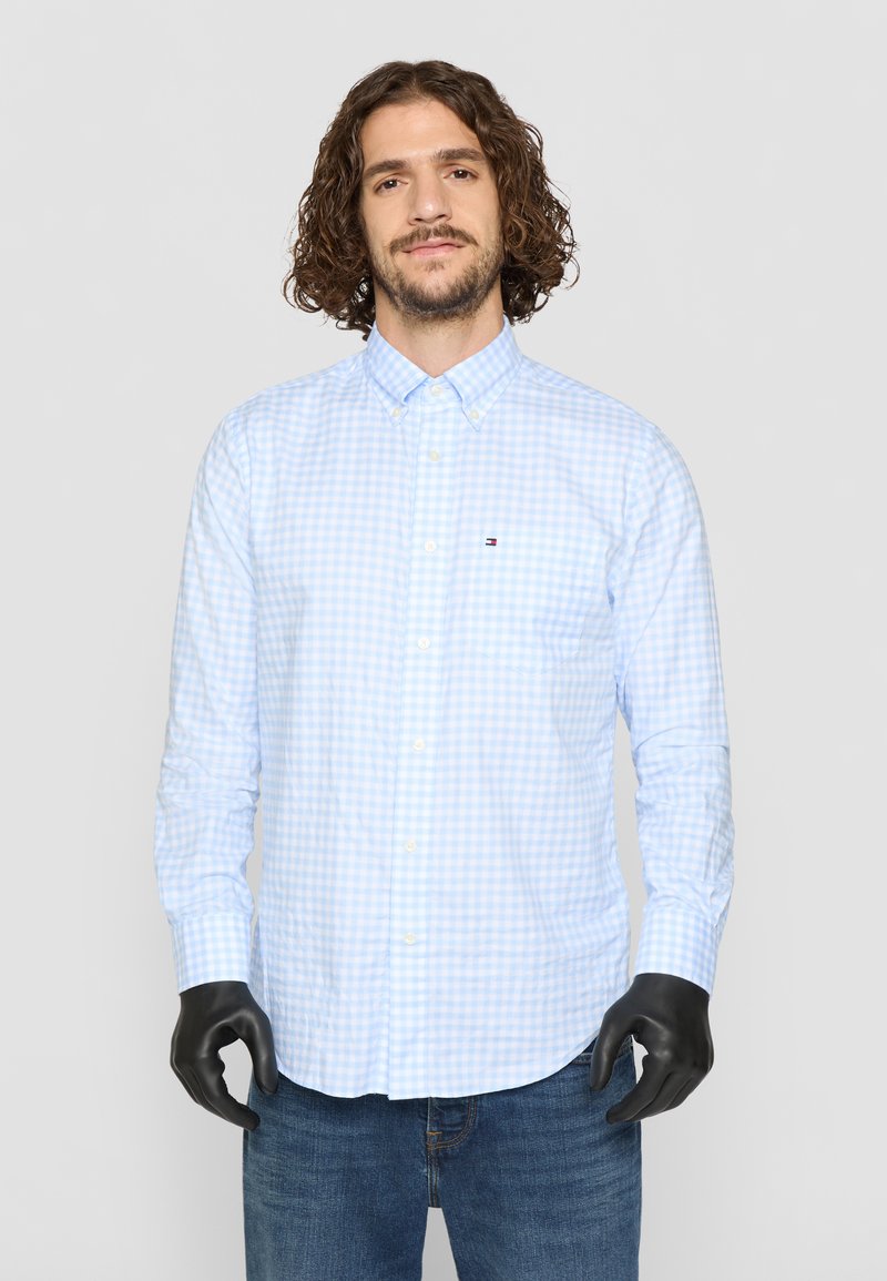 Lyseblå gingham ternet skjorte med knap-ned krave, lange ærmer og et lille logo. Tæt design i bomuldsstof; glat tekstur.