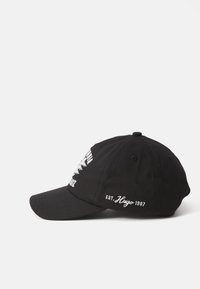 Black baseball cap with a curved brim, featuring white embroidered text and graphics on the front and side panels. Made of cotton.
