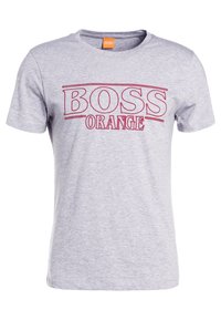 Světle šedé tričko s krátkým rukávem s červeným textem "BOSS ORANGE" na hrudi a oranžovou nálepkou uvnitř výstřihu.