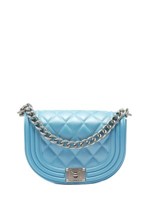 Weiche, blaue, gestepelte Handtasche mit einem silbernen Kettenriemen und einem glänzenden Metallverschluss mit einem Logo, vor einem weißen Hintergrund.