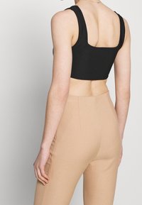 Černý zkrácený top s čtvercovým výstřihem a širokými ramínky, zkombinovaný s béžovými hihhote pants s texturovanou látkou.