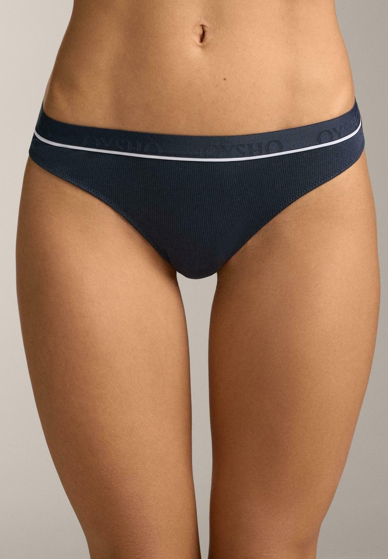 Marineblauer gerippter Bikini-Slip mit einem kontrastierenden weißen, elastischen Bund, der ein eingeprägtes Markenlogo aufweist. Glatte Textur und figurbetontes Design.