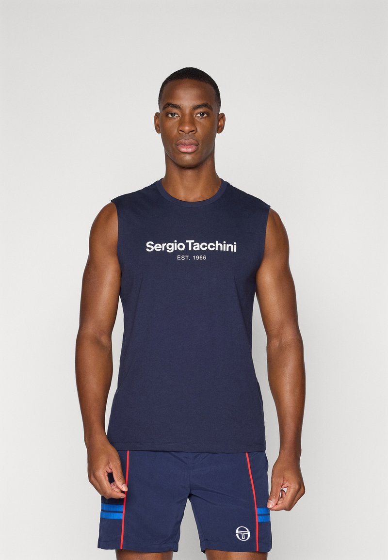 Marineblå ærmeløs skjorte med hvid "Sergio Tacchini EST. 1966" logo. Bæres med matchende marineblå shorts, der har rød og blå striber samt logo.