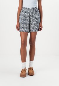 Patterned shorts in navy and white, featuring a drawstring waist. Paired with white socks and tan shoes with a textured sole.