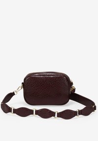 Pequeño bolso cruzado de cuero texturizado marrón oscuro con un zipper dorado y una correa ancha que presenta segmentos de cuero y anillos dorados.
