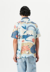 Cămașă cu mânecă scurtă, decorată cu un model abstract multicolor, cu forme în nuanțe de albastru, roz și bej, realizată dintr-un material ușor, cu o croială lejeră.