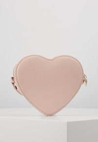 Różowa torba w kształcie serca wykonana z teksturowanej skóry z złotym zamkiem i paskiem. Gładka powierzchnia z kontrastującymi szwami.