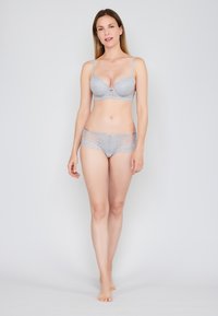 Lichtgrijze lingerie set met een bh met kantafwerking en bijpassende slip. De bh heeft gevormde cups en verstelbare schouderbandjes. Glad stofoppervlak.