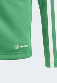 Canottiera sportiva verde in tessuto strutturato, con strisce bianche sui lati e logo "AEROREADY" sul bordo inferiore.