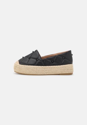 Sort quiltet slip-on sko med små nitter og tyk flettet lys beige platformsål.