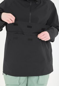 Mustat vedenpitävät takit, joissa on korkea kaulus, tarranauhalla varustetut taskut ja säädettävät sulkijat. Yhdistetty mintunvihreisiin cargo-housuihin.