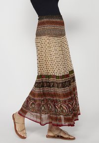 Long, flowy skirt featuring a multicolored patchwork design with a smocked waistband, lightweight fabric, and floral patterns in red and green.