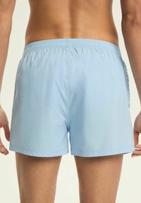 Jasnoniebieskie kąpielówki z elastycznym pasem, miękką fakturą i bocznymi kieszeniami, z prostym wzorem i prostym krojem nogawki.